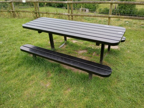  Rectangular black steel picnic table with horizontal slats and two steel horizontal slat benches attached either side.